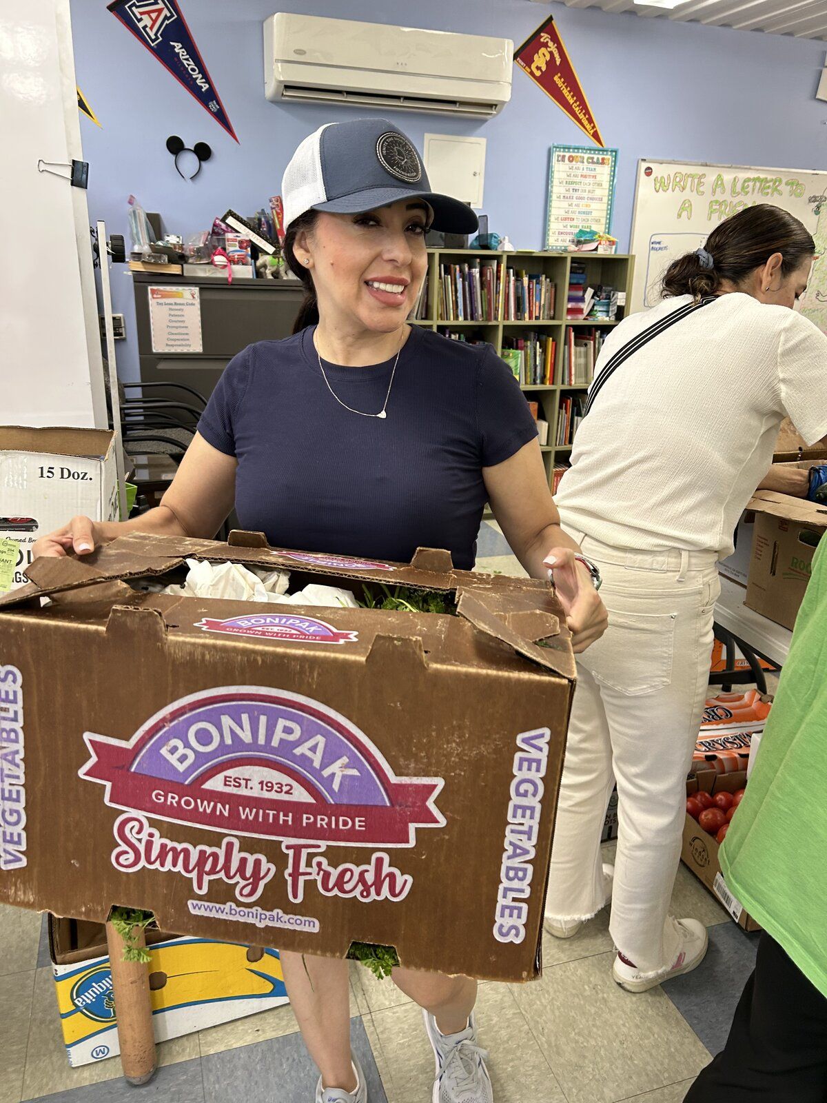 An Ignite volunteer carrying a box of fresh vegetables for outreach